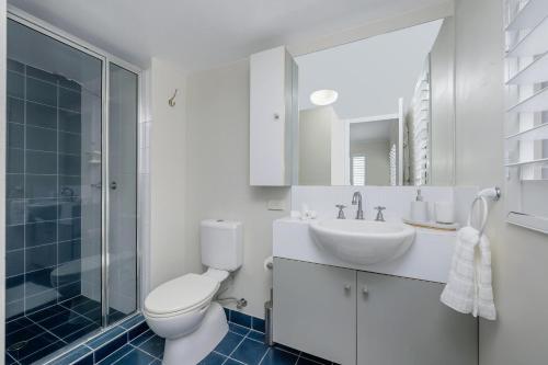 a bathroom with a toilet and a sink and a shower at City Love Affair On Stanley in Townsville