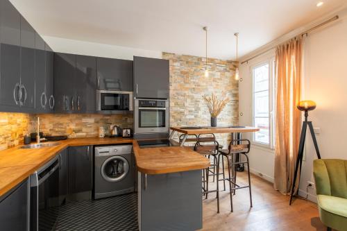 une cuisine avec des armoires noires et un comptoir en bois dans l'établissement Amazing loft in the vibrant area near the famous Bastille's Place, à Paris