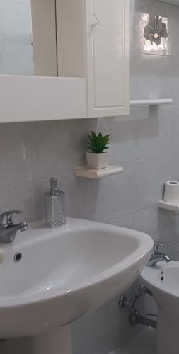 a white bathroom with a sink and a mirror at SWEET Apartment in San Giorgio Ionico