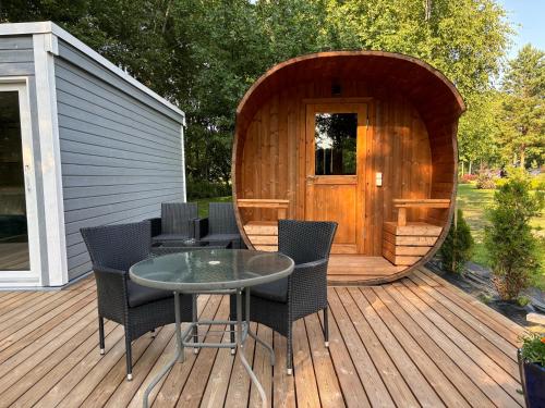 a wooden deck with a table and chairs in front of a sauna at Pauna Puhkemaja in Tori