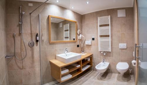 a bathroom with a sink and a shower and a toilet at Hotel Arnaria in Ortisei