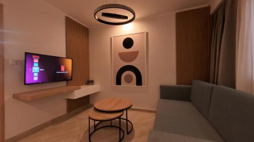 a living room with a couch and a stool and a tv at Mouson Luxury Apartment in Kavala