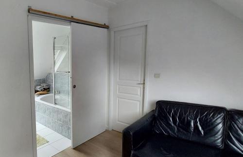 eine schwarze Ledercouch in einem Zimmer mit Badewanne in der Unterkunft Maison mer et campagne in Pluvigner