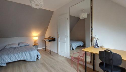 ein Schlafzimmer mit einem Bett, einem Schreibtisch und einem Spiegel in der Unterkunft Maison mer et campagne in Pluvigner