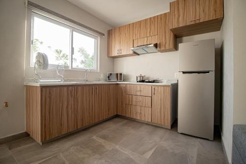 a kitchen with wooden cabinets and a white refrigerator at Memora Hotel & Villas Chapala in Chapala