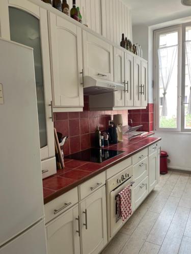 - une cuisine blanche avec des placards blancs et du carrelage rouge dans l'établissement charming and cozy, à Marseille