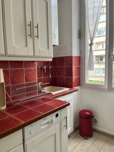 - une cuisine avec des placards blancs et du carrelage rouge dans l'établissement charming and cozy, à Marseille