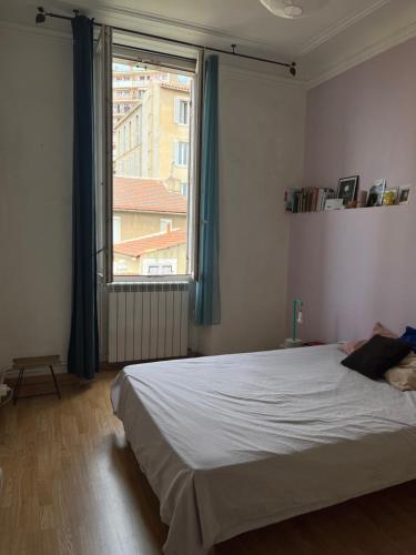 une chambre avec un lit et une grande fenêtre dans l'établissement charming and cozy, à Marseille