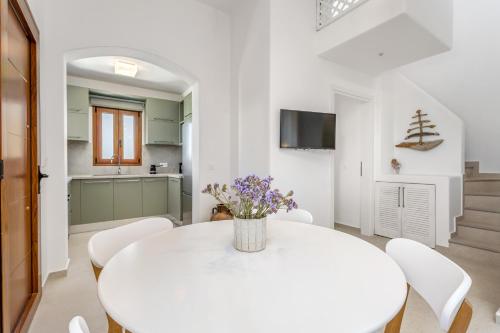a white dining room with a white table and white chairs at Anemonisia Skyrian Living in Skiros