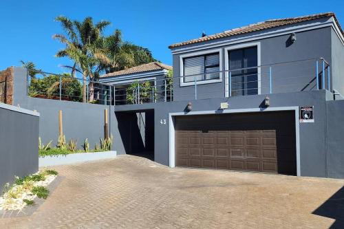 a gray house with a garage and a tree at Champers with a view in Cape Town
