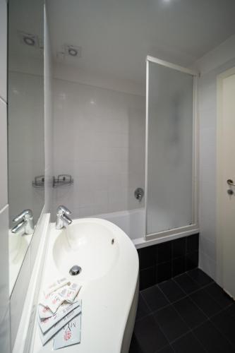 a white bathroom with a sink and a mirror at Hotel Trieste in Rimini