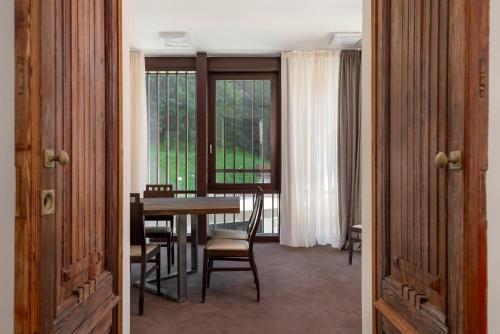 a dining room with a table and chairs and windows at Villa Carona Hotel & Spa in Carona