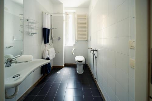 a white bathroom with a sink and a toilet at Hotel Trieste in Rimini