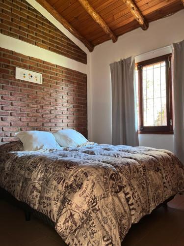 a bed in a bedroom with a brick wall at La Casita de Lorena in El Bolsón