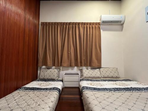 two beds in a small room with a curtain at Villa Klebang Beach 25Pax 6Bedroom Indoor Pool Full AirConditioned near TOWN in Melaka