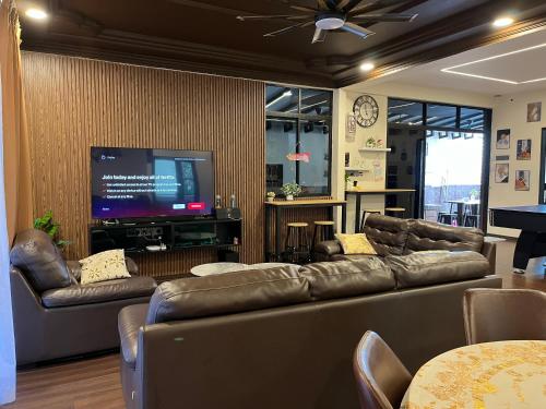 a living room with leather couches and a flat screen tv at Villa Klebang Beach 25Pax 6Bedroom Indoor Pool Full AirConditioned near TOWN in Melaka