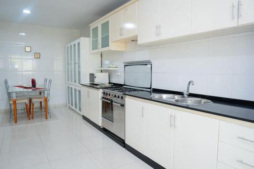 a white kitchen with a sink and a stove at Nice And Modern with king size bed in Praia