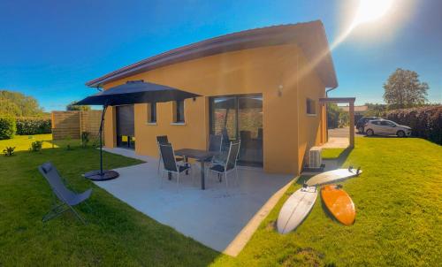 une maison avec une table, des chaises et un parasol dans l'établissement Maison mitoyenne, 2 chambres, 4 personnes, à Saint-Martin-de-Seignanx