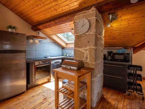 une cuisine avec une horloge sur un mur en pierre dans l'établissement Appartement duplex le montagne de la villa Chanterive, à La Bourboule