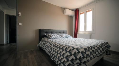 a bed in a bedroom with a window and a bedspread at Agréable Villa pour 8 personnes in Pont-du-Château