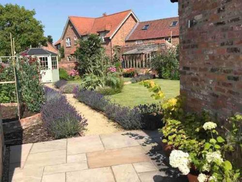 a garden with flowers and a brick building at Pretty Garden Cottage in Tollerton
