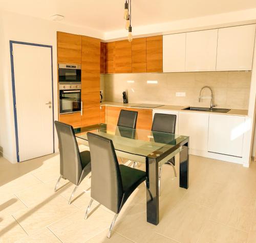 une cuisine avec une table et des chaises en verre dans l'établissement Maison mitoyenne, 2 chambres, 4 personnes, à Saint-Martin-de-Seignanx