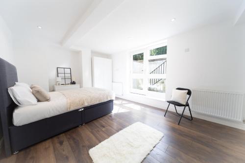 a white bedroom with a bed and a chair at Excellent 3 bedroom, 3 baths, City Centre, voucher available in Leeds