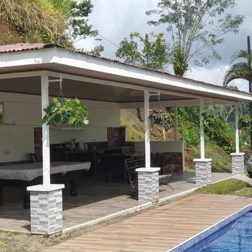 a pavilion with a table and a swimming pool at Lumbres Arenal in Fortuna
