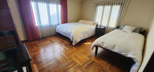 a bedroom with two beds and a wooden floor at Raven La Paz in La Paz