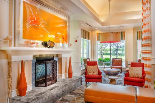 a living room with a fireplace and red chairs at Hilton Garden Inn St. Louis/Chesterfield in Chesterfield