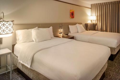 a hotel room with two beds and a chair at Hilton Garden Inn St. Louis/Chesterfield in Chesterfield