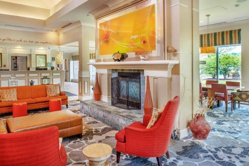 a living room with a fireplace and red chairs at Hilton Garden Inn St. Louis/Chesterfield in Chesterfield