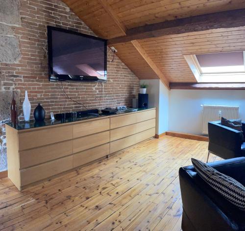 un salon avec une grande télévision sur un mur en briques dans l'établissement Appartement duplex le montagne de la villa Chanterive, à La Bourboule