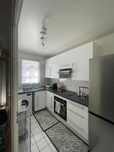  La cuisine est équipée de placards blancs et d'un réfrigérateur. dans l'établissement Lac Zen & Frissons des JO 2024, à Épinay-sur-Seine