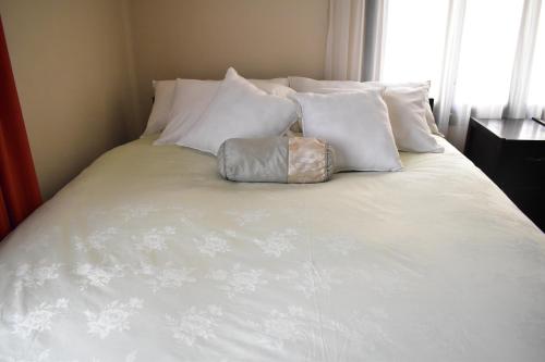 a white bed with white pillows and a purse on it at Raven La Paz in La Paz