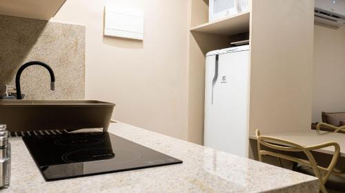 a kitchen with a counter with a sink and a refrigerator at Beach Class Internacional - Studio Vista Mar em Boa Viagem por Yolo in Recife