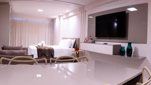 a white room with a bed and a tv at Beach Class Internacional - Studio Vista Mar em Boa Viagem por Yolo in Recife