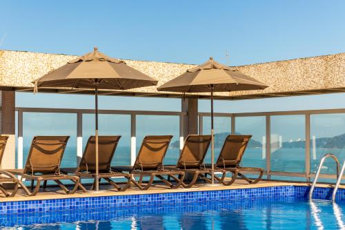 a group of chairs and umbrellas next to a swimming pool at Parque Balneário Hotel Santos by Castelo Itaipava in Santos