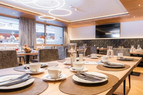 a dining room with a large wooden table with chairs at Hotel B&B VILLA-ALPIN in Grossarl