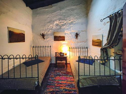 Un dormitorio con dos camas y una mesa con lámpara. en Casa das Romãs, en Salvada