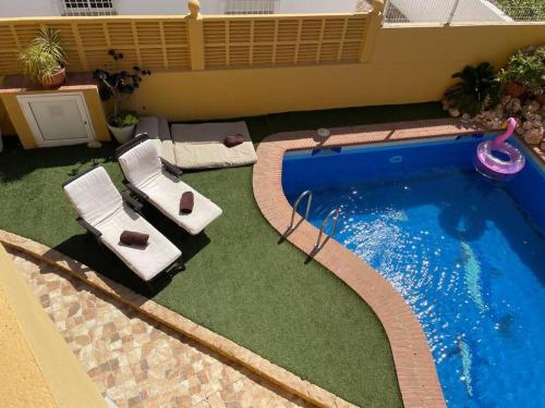 a swimming pool with two lounge chairs next to it at Villa Reencuentro Mojácar Playa in Mojácar
