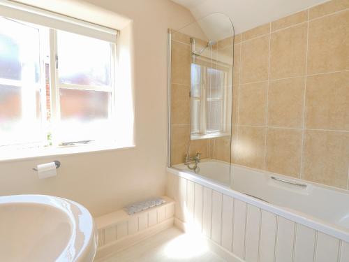 a bathroom with a tub and a sink and a window at Crab Corner in Wells next the Sea