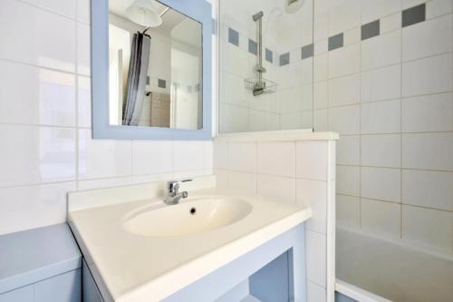 une salle de bain blanche avec un lavabo et un miroir dans l'établissement Résidence Les Grands Pins - maeva Home - Appartement 2 Pièces 5 Personnes - Confort MAE-1502, à Maubuisson