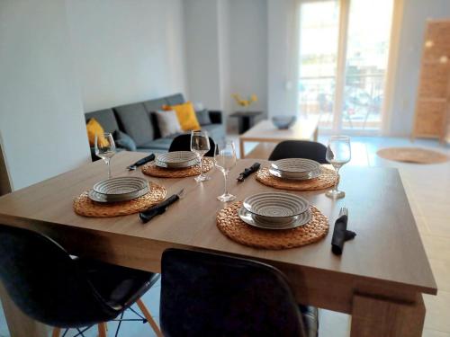 a wooden table with plates and wine glasses on it at Angela's Apartment in Chalkida