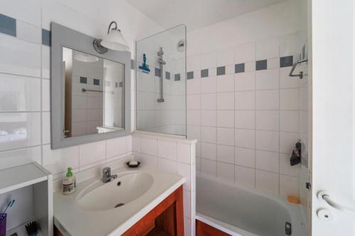 une salle de bain avec un lavabo, une baignoire et un miroir dans l'établissement Résidence Les Grands Pins - maeva Home - Appartement 2 pièces 4 personnes Sélection MAE-1805, à Maubuisson