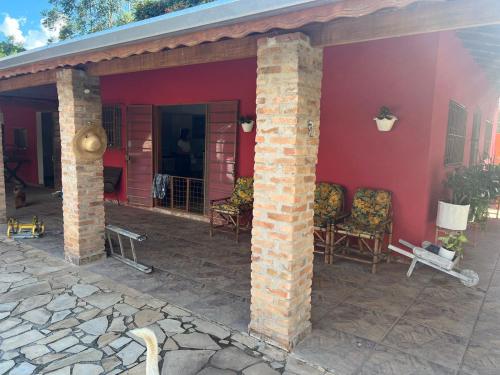 a red house with chairs on a patio at Chácara Segundo Sol in Caçapava