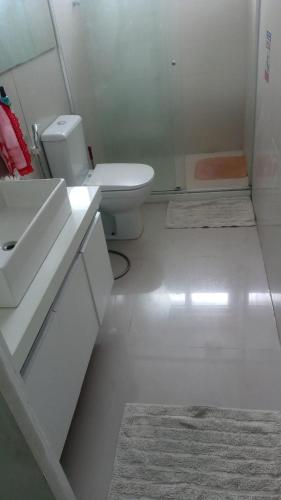 a white bathroom with a sink and a toilet at PEQUENO QUARTO individual-PERTO DO CENTRO DE CONVENÇÕES-FENEARTE - RECIFE - ventilador,TV,mesa de trabalho in Recife