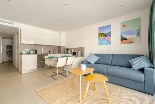 un salon avec un canapé bleu et une cuisine dans l'établissement Magnifique 2 pièces avec balcon proche Martinez et Croisette, à Cannes