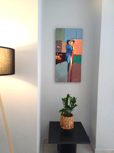 a painting on a wall next to a table with a plant at Angela's Apartment in Chalkida