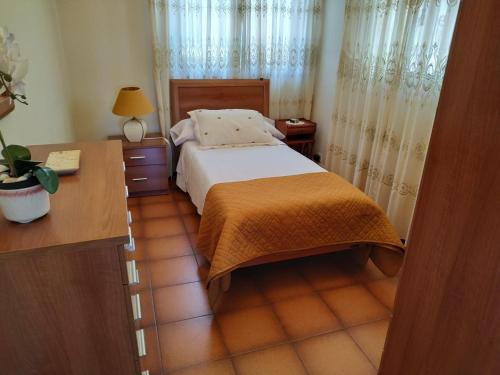 a bedroom with a bed and a desk and curtains at Villa Sara in Ribadeo